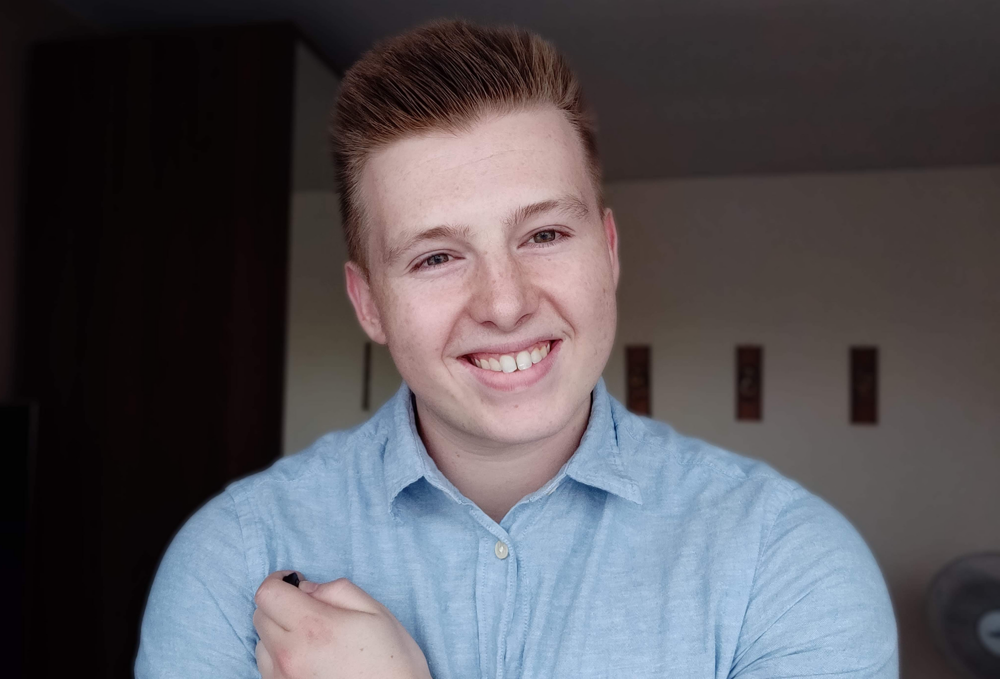 Self portrait of PEG smiling into the camera wearing a light blue shirt with collar